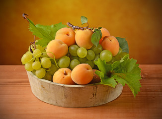 ciotola di legno con uva e albicocche