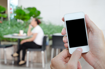 Hands holding smart phone with abstract blurred of woman at coffee shop.