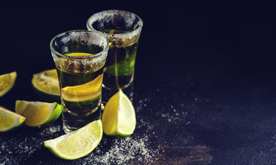 Mexican Gold Tequila with lime and salt on wooden table, selective focus. Toned. Retro style...