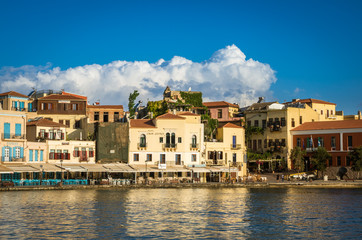 Fototapeta na wymiar View of the old venetian port of Chania on Crete island, Greece. Tourists relaxing on promenade.