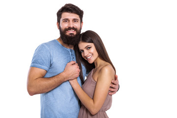 Fototapeta premium Happy loving couple. Portrait of beautiful young loving couple bonding to each other while standing against white background.