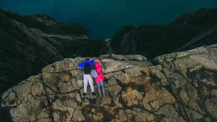 young couple lying on the edge of a cliff. Cliff Preikestolen in