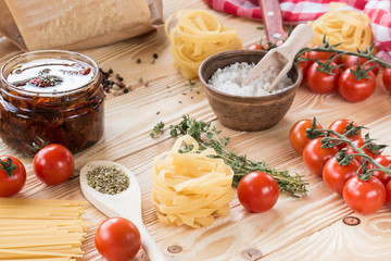 cherry tomatoes, dried tomatoes in glass jar on wooden table, Parmesan, basil leaf,  thyme, rosemary, prosciutto, pasta, spaghetti, italian food concept