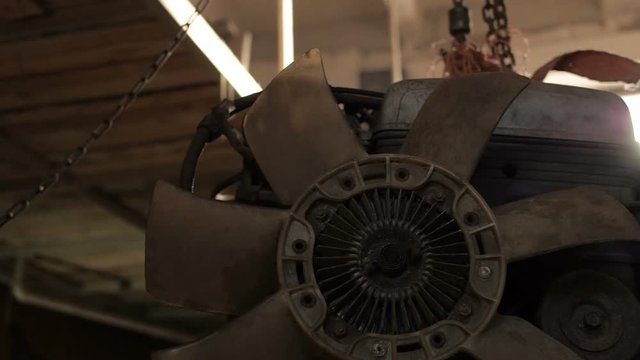 Girl in jeans rummaging in the naked engine suspended in the garage