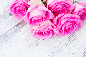 Pink fresh roses in water drops on white wooden aged desktop