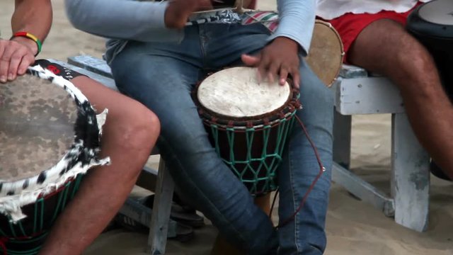 Unidentified man playing on drum at the beach.