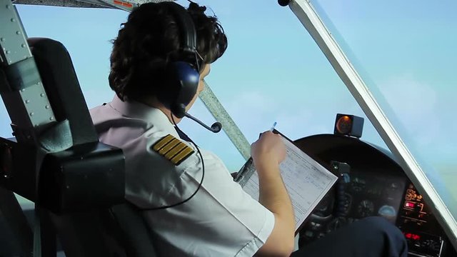 Professional pilot filling out flight papers while flying airplane, profession