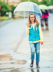 Portrait of beautiful young pre-teen girl with umbrella under rain. 