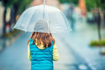 Portrait of beautiful young pre-teen girl with umbrella under rain. 