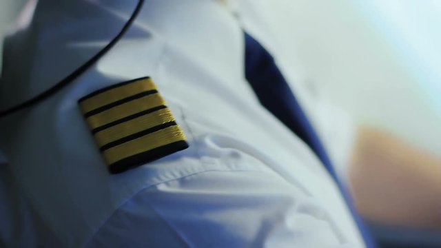Airline captain sitting in cockpit, adjusting uniform, getting ready for takeoff