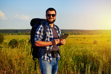 Naklejka na ściany i meble Man in sunglasses with rucksack standing in the field with data