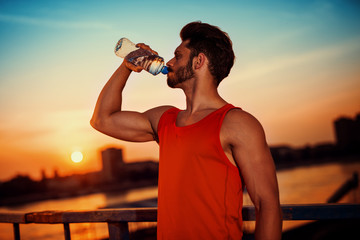 Athletic sport man drinking water from a bottle