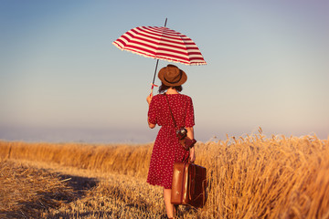 young woman with suitcase, umbrella and camera