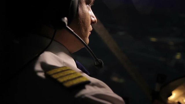 Attentive captain pilot in headset navigating huge airliner at night, job duties