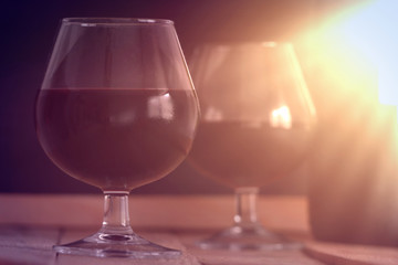 Two wine glass and a bottle on a wooden table against a black background. Sun light. Empty copy space for editor's text.