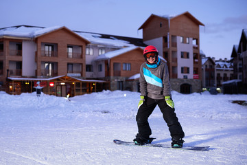 Pretty Girl snowboarder stands on front of hotel ski resort