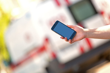 People hand with smartphone calling at emergency car background