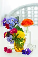 Colorful vibrant cut flowers in vases on white desktop