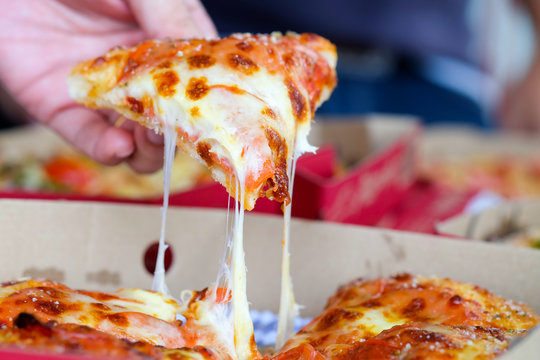 Man's Hand Holding A Pizza Out Of The Box