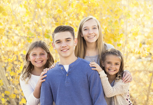 Beautiful Portrait of smiling happy kids outdoors. Four siblings standing together for a cute picture on a warm fall day