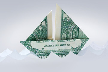 Dollar origami bill sailboat in paper waves. Paper ship. Moneygami background.