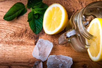 Cold fresh lemonade drink and ice cubes on wooden background