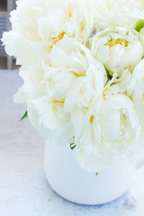 White bfresh looming peony flowers in vase on table close up
