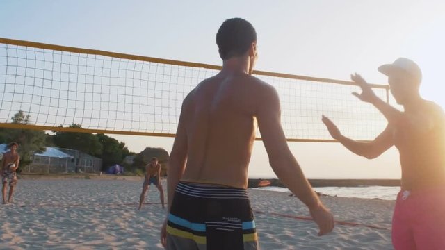 Beach volleyball players giving high fives during the game, slow motion