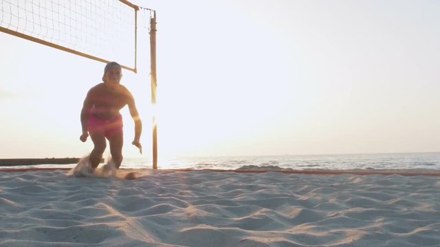 Volleyball player jumping to cath the ball on the beach during sunrise or sunset