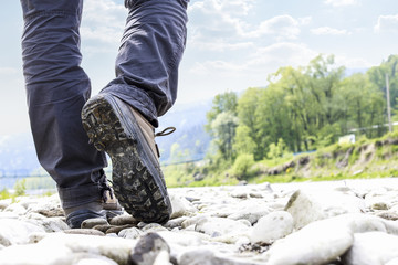 Traveller walking at the riverside. Hiking boots on bedrock.