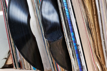 Retro styled image of a collection of old vinyl record lp's with sleeves on a wooden background.  Copy space