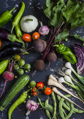 Assortment of fresh garden vegetables on dark background. Top view