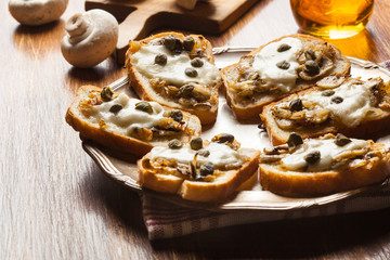 Crostini with fried mushrooms, onion and mozzarella cheese