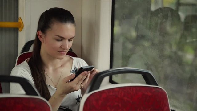 Young girl using smart phone during bus ride, Beautiful woman travelling in urban transport and using her mobile phone