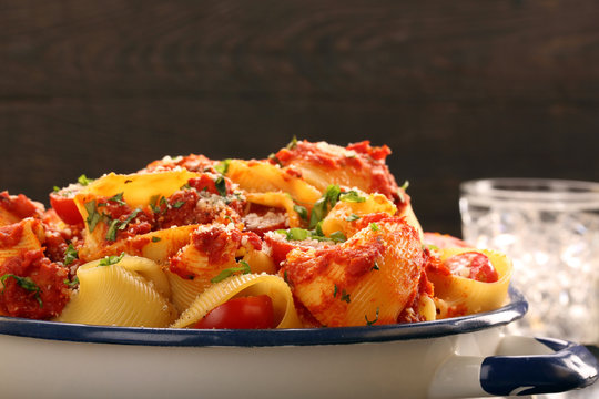 Lumaconi pasta with tomato sauce on wooden background