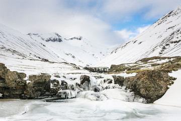 Amazing frozen waterfall near Hofn. Winter Icelandic landscape.