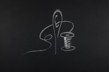 Group of sewing objects lying flat on a black chalkboard backgro