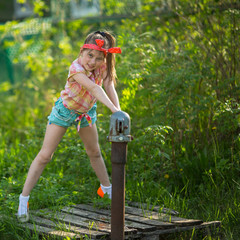 Little naughty girl near the water pump in the village.