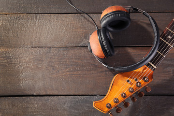 Guitar and headphones on wooden background