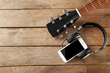 Smartphone with headphones on wooden background
