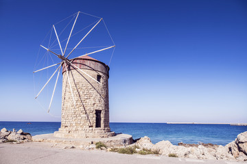 Fototapeta na wymiar The tower with the windmill on the sea background