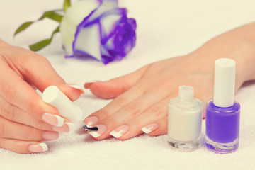 Beautiful female hand with french manicure. Woman applying top nail polish