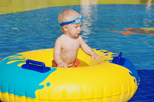 Happy family has a fun in beach pool - baby boy sunbathing, swim with inflatable toy. Healthy lifestyle, active parent, people water sports activity and swimming lesson on summer holiday with child