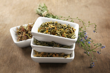 Natural flower and herb selection in ceramic bowls on wooden background
