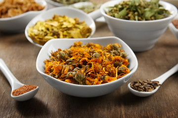 Natural flower and herb selection in ceramic bowls on wooden background