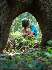 Naklejka na ściany i meble Little boy lost in the woods and sits having embraced her legs