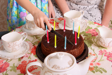 the hands of girls cut the cake with candles