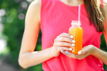 Fototapeta premium Sportswoman drinking detox juice on street
