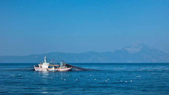 Fishing boat with nests at sea in front of mountain Athos, Greece