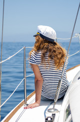 Young marine style woman is sitting on the boat and looking forward